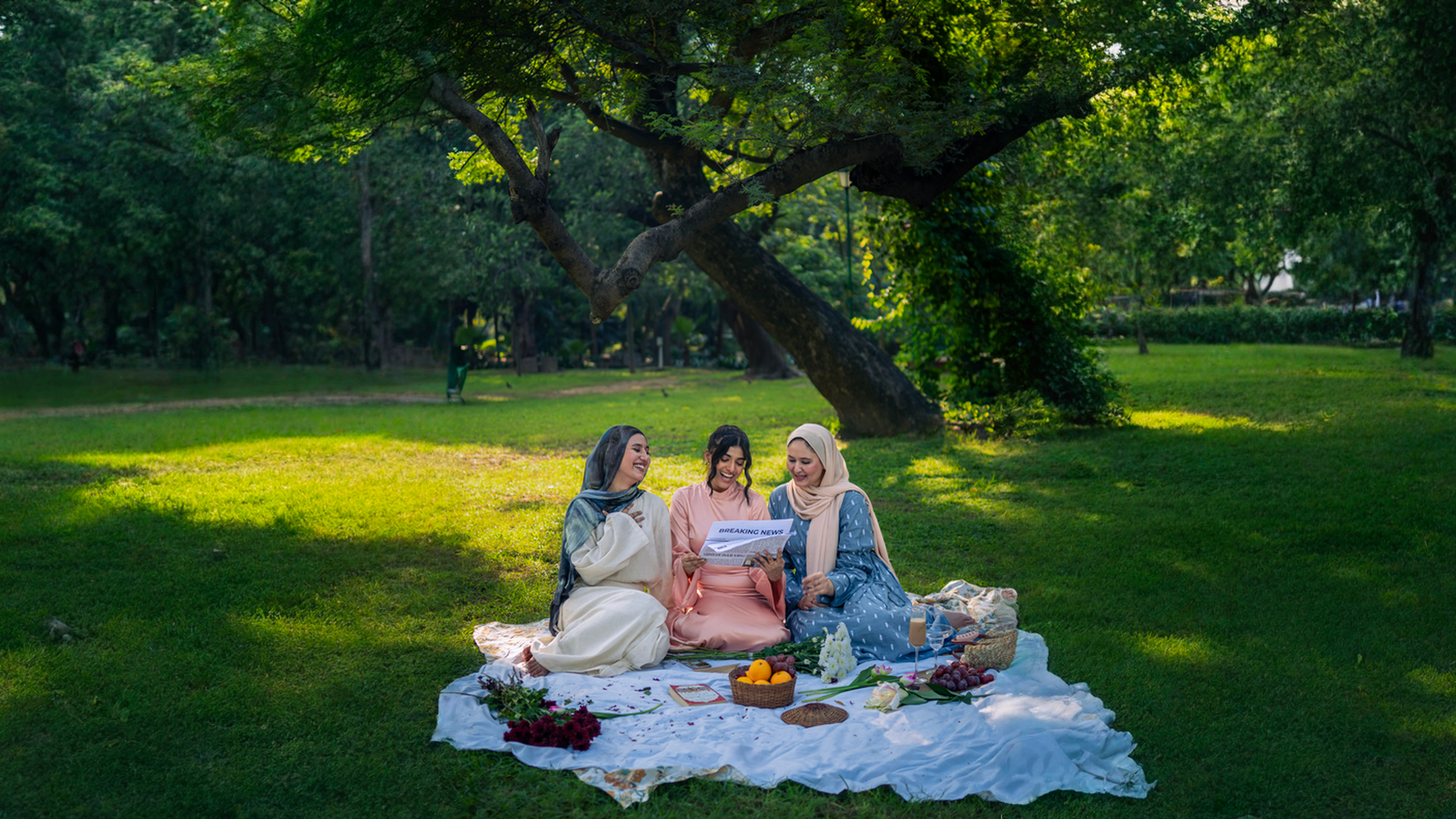 Three women sitting on a picnic blanket in a park